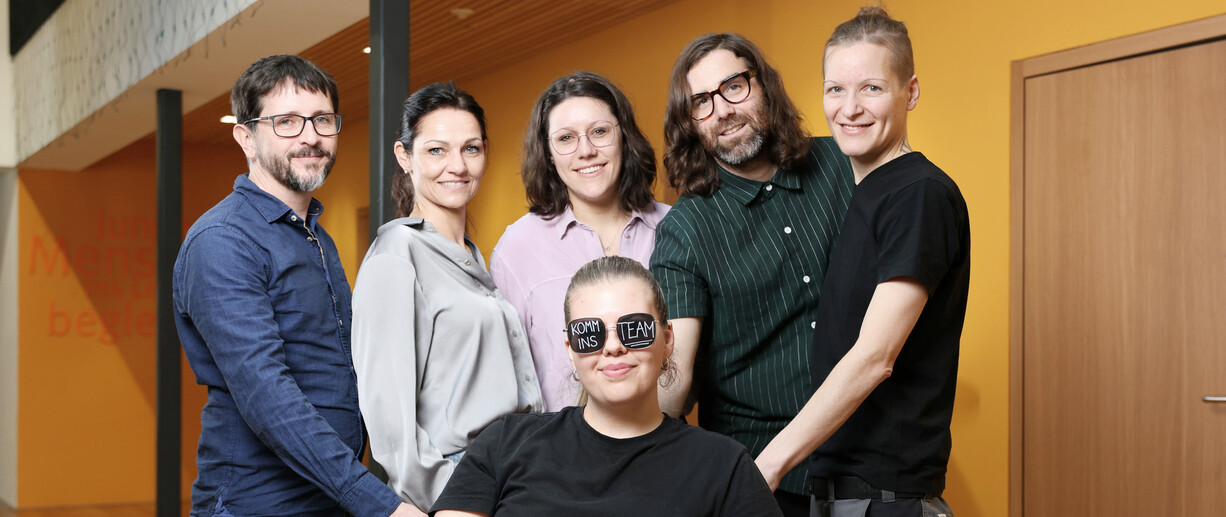 6 Mitarbeiterinnen, eine mit Brille und Aufschrift Komm ins Team